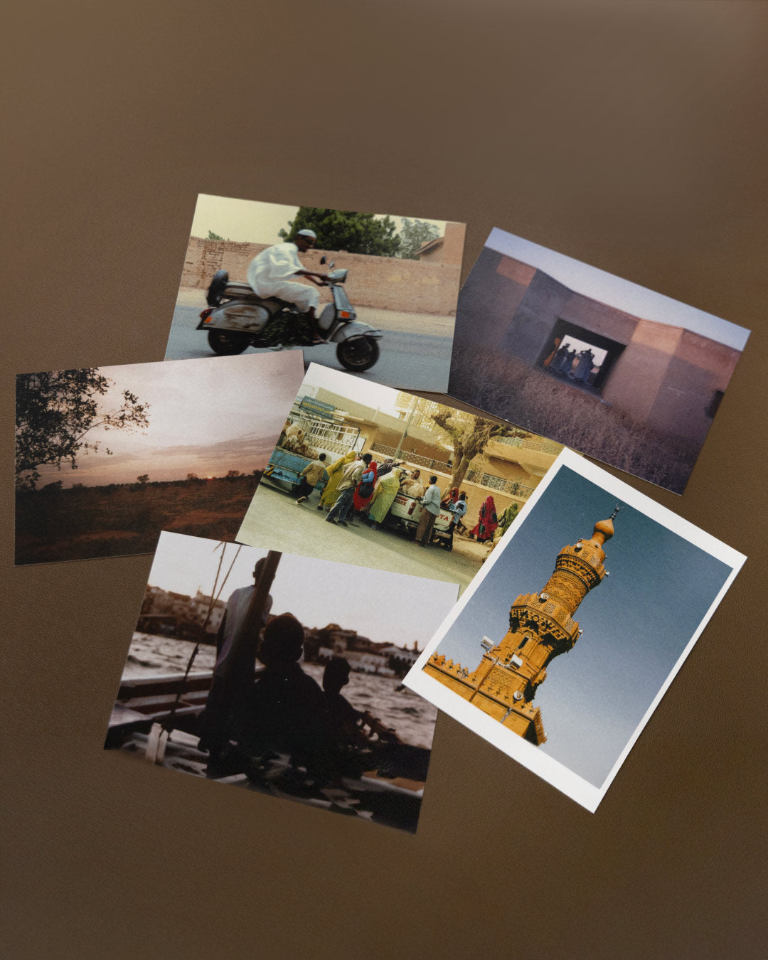 Collection of photographs printed as postcards on a brown background inspired by sudanese culture on a brown bag as part of islamic relief uk new sudan souq collection