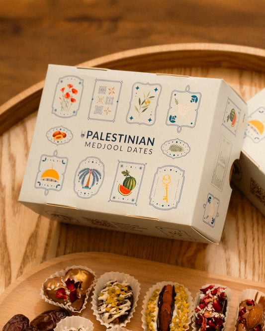 an angled view of a 900g box of palestinian medjool dates with a lid that has designs inspired by palestinian culture
