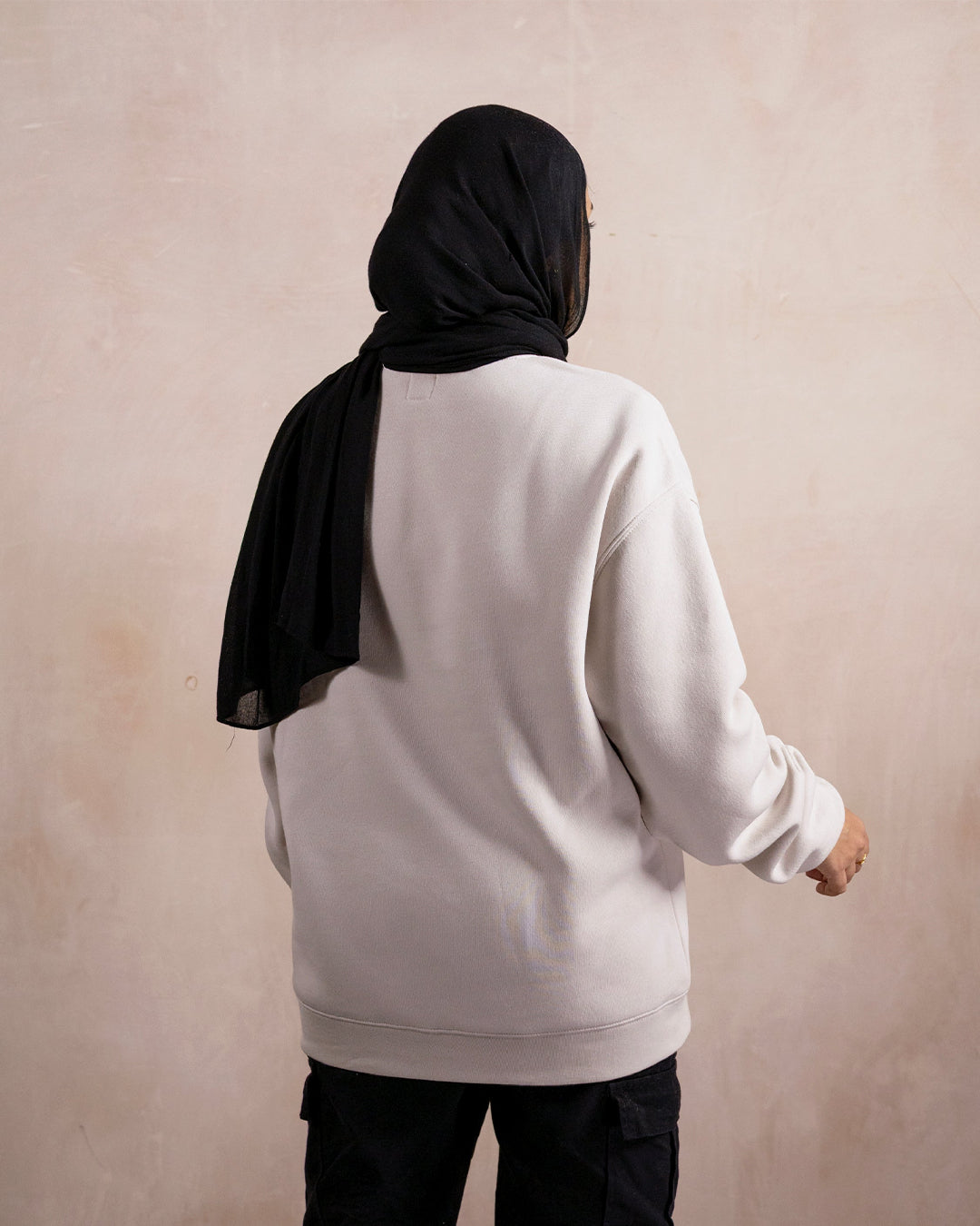 the back of a woman wearing a light beige sweatshirt 
