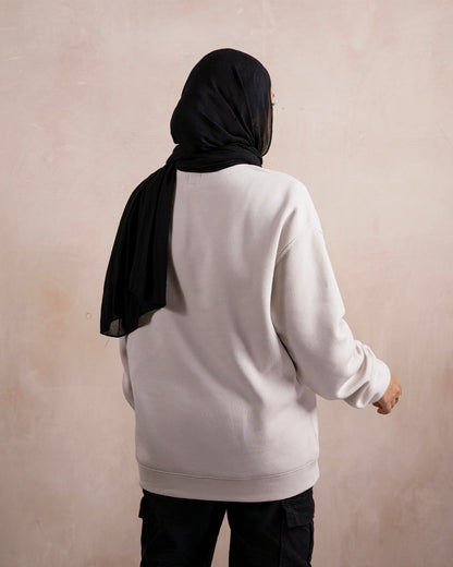 the back of a woman wearing a light beige sweatshirt 