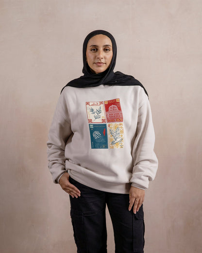 a woman wearing a light beige sweatshirt printed with a design inspired by palestinian culture