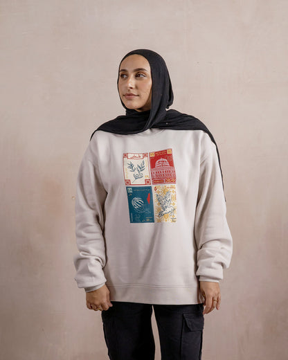 a woman wearing a light beige sweatshirt printed with a design inspired by palestinian culture