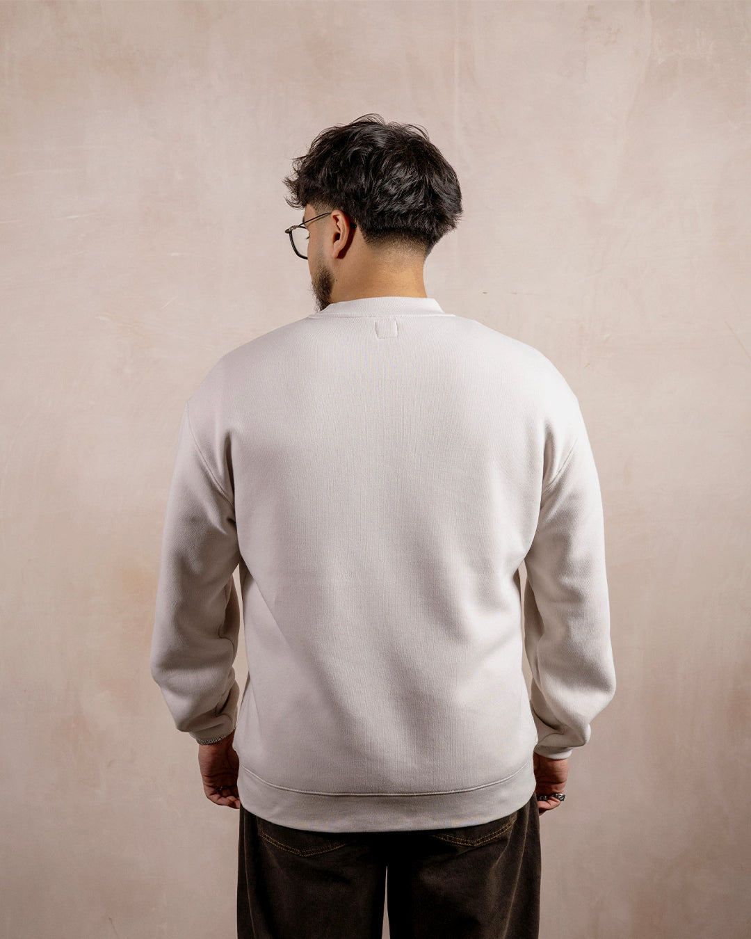 the back of a man wearing a light beige sweatshirt