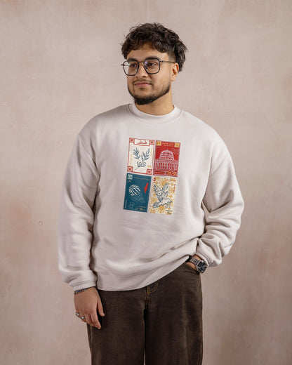 a man wearing a light beige sweatshirt printed with a design inspired by palestinian culture with one hand in his pocket