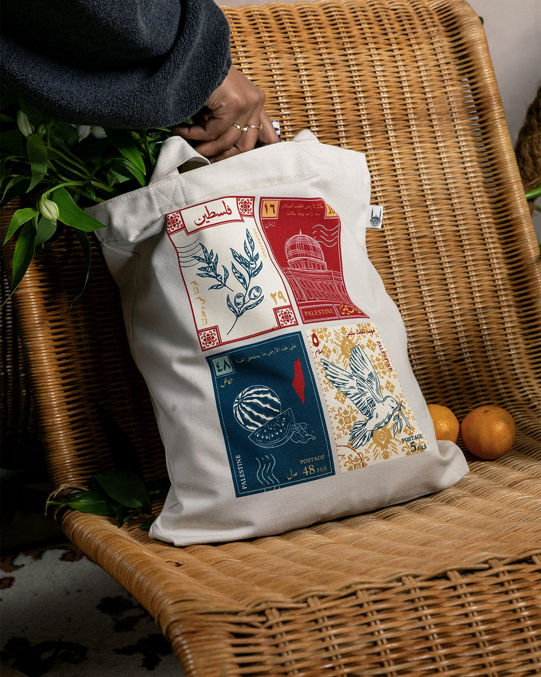a tote bag with a design inspired by palestinian culture hanging with purple flowers inside